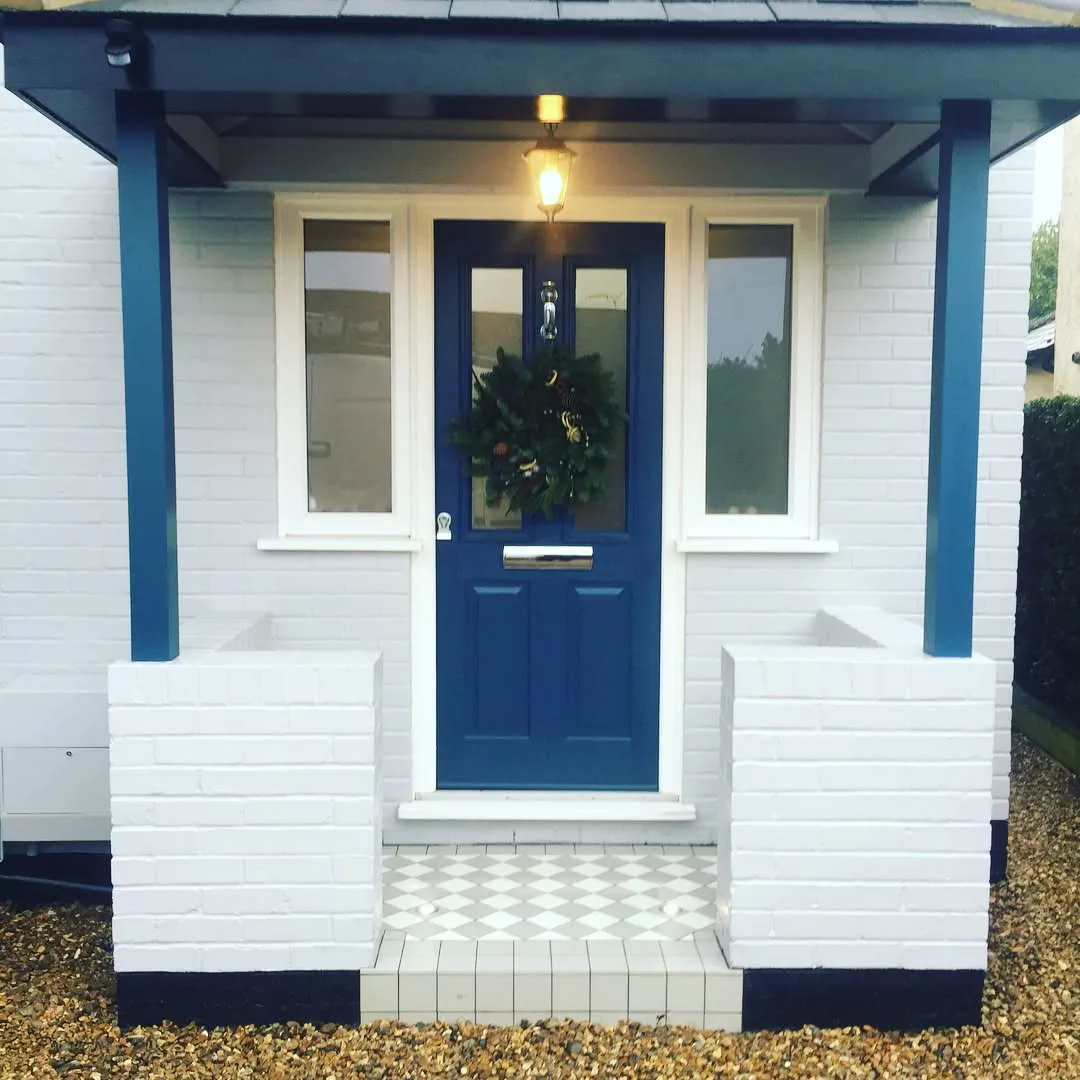 Finished porch with a navy front door, porch pendant light and up-lit tiled step