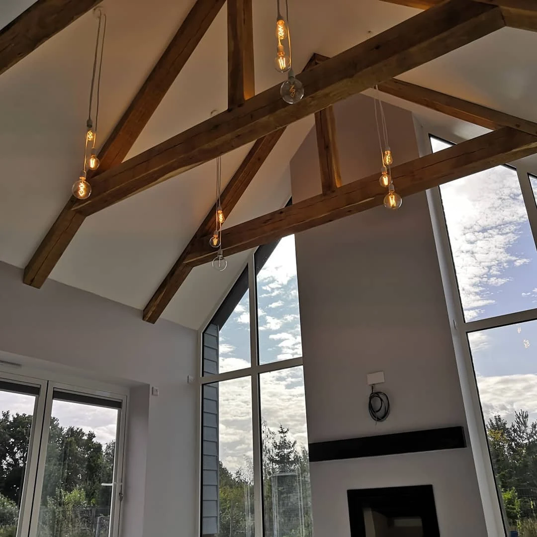 Vaulted oak-beam extension ceiling with hanging filament pendant lights